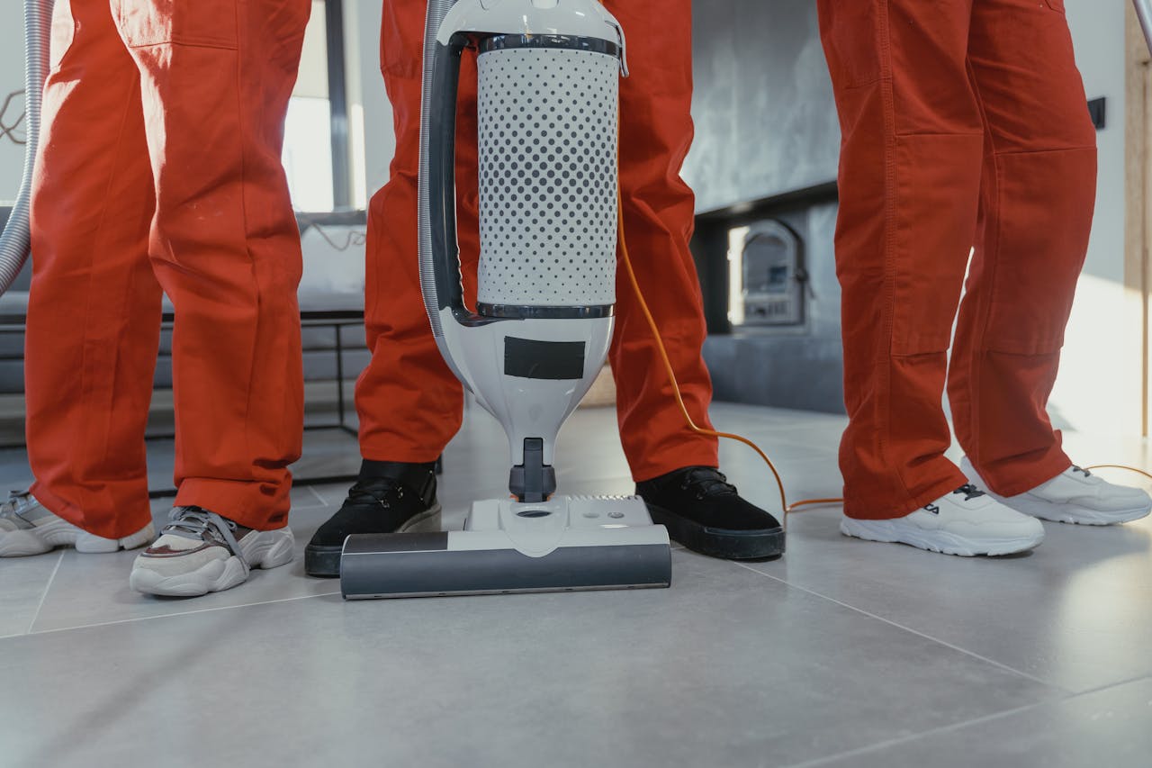 cta-bg Team of professional cleaners in red uniforms using a vacuum cleaner indoors.